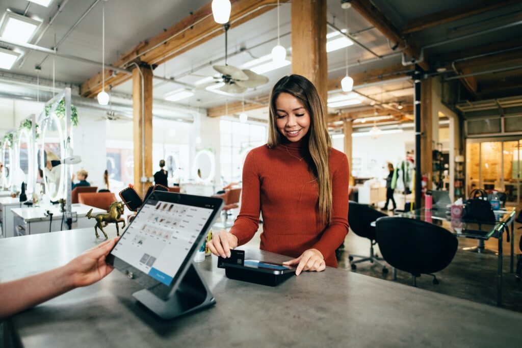 Uma mulher realiza um pagamento com cartão no balcão de uma loja